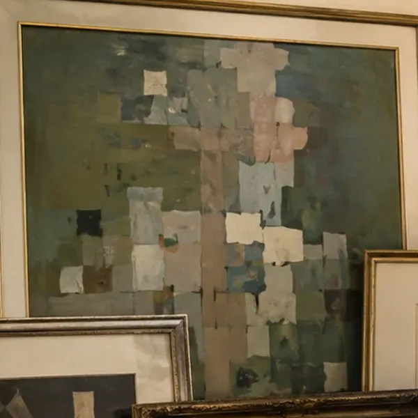 A large abstract painting in muted greens and pinks in a gold frame.